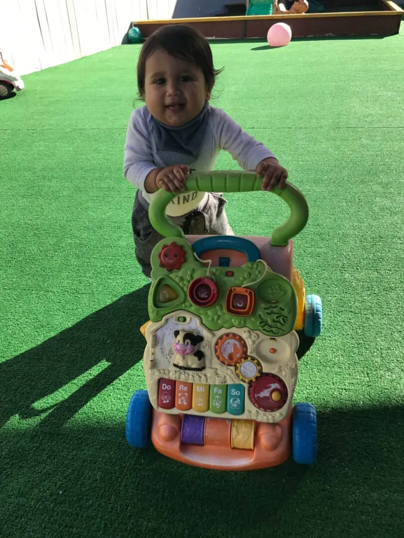 Child playing with colorful push toy outside.